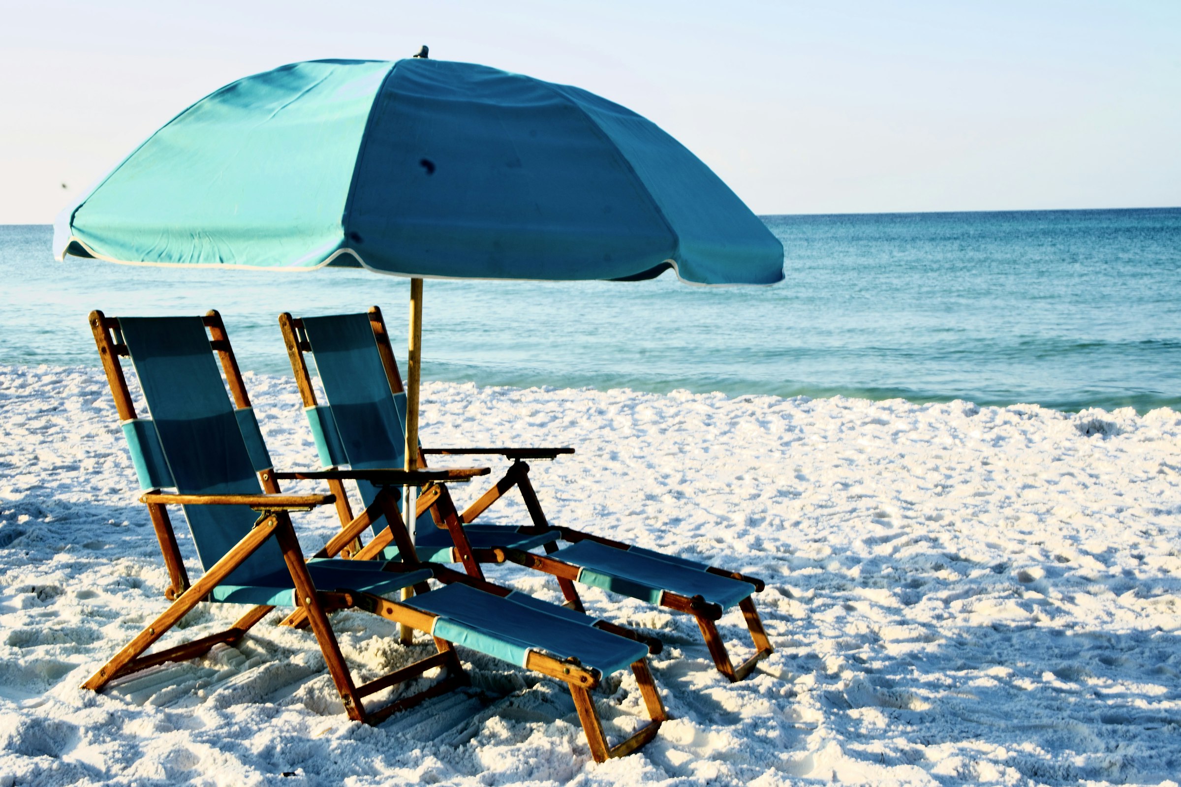 Beach umbrellas on white sand by emerald water on the Florida Gulf Coast
